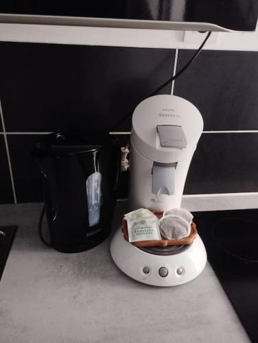 un robot culinaire posé sur un comptoir à côté d'une tasse dans l'établissement Appartement coeur de ville!, à Foix