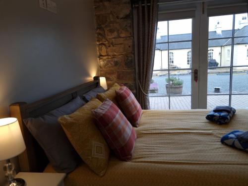 ein Schlafzimmer mit einem Bett mit Kissen und einem Fenster in der Unterkunft Cobbles cottage - 2 bedroom stone built cottage in Ballynahinch