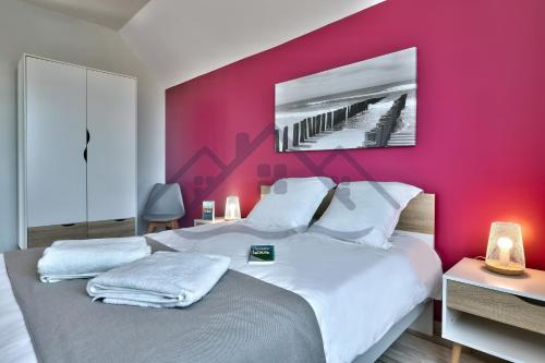 a bedroom with a large bed with a red wall at LocaLise - M2C - Ty Ma Bro -Maison avec extérieur entièrement clos - Wifi inclus - Draps inclus- Animaux bienvenus in Le Guilvinec