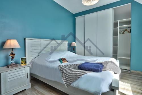 a bedroom with a bed with a blue wall at LocaLise - M2C - Ty Ma Bro -Maison avec extérieur entièrement clos - Wifi inclus - Draps inclus- Animaux bienvenus in Le Guilvinec