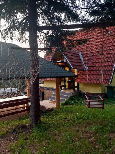 a hammock in front of a house with a roof at Tarski vrh in Bajina Bašta