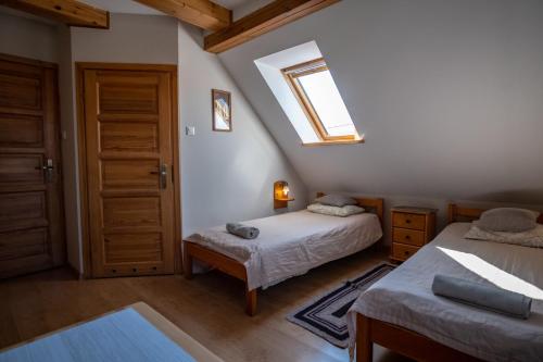 a attic bedroom with two beds and a window at Siedlisko Leszczewek in Leszczewek