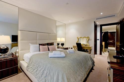 Schlafzimmer mit einem großen weißen Bett und einem Schreibtisch in der Unterkunft Luxurious West Kensington Flat with City Views in London