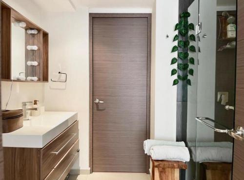 een badkamer met een houten deur en een wastafel bij Departamento equipado en Santa Fe con servicio shuttle por la zona in Mexico-Stad
