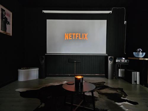 a room with a table and a screen with the text netflix at BLACK BOX CINEMA appartement avec balnéo in Épinal