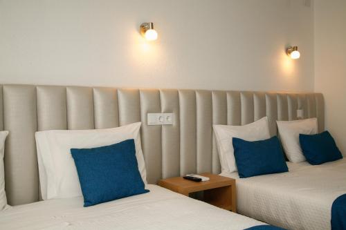 a hotel room with two beds with blue pillows at Nova Delpa AL in Caldas da Rainha