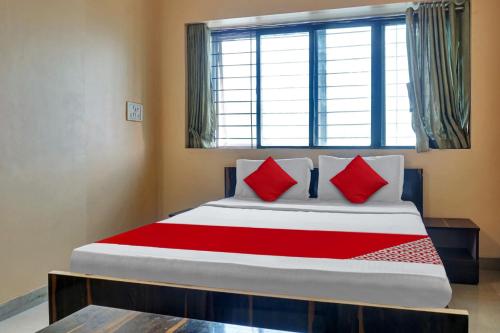 1 dormitorio con 1 cama grande con almohadas rojas en OYO Savanna Garden Lodge en Pune