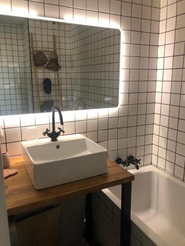 une salle de bain avec un lavabo, un miroir et une baignoire dans l'établissement Palais du casino, à Palavas-les-Flots