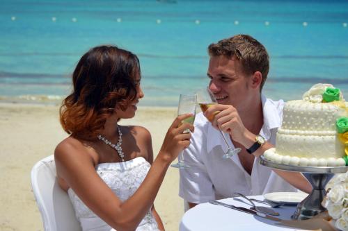 a bride and groom drinking champagne at a wedding cake at Sunset at the Palms Resort - Adults Only - All Inclusive in Negril