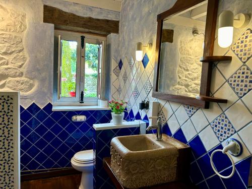 uma casa de banho com paredes em azulejos azuis e brancos e um lavatório. em Antaviana Cantabria em Cabezón de la Sal
