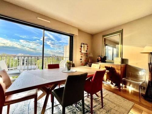 une salle à manger avec une table et une grande fenêtre dans l'établissement Jerickais Appartement à Rueil, à Rueil-Malmaison