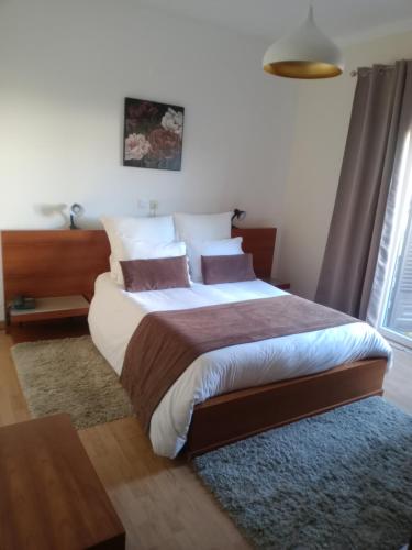 1 dormitorio con 1 cama grande con sábanas y almohadas blancas en Casa Morgado en Almeida