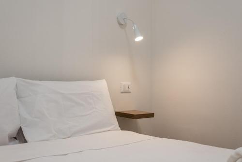 a bed with a white pillow and a light on the wall at Quattro Canti rooms in Palermo