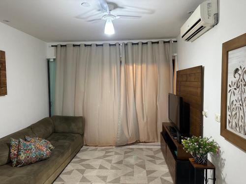 uma sala de estar com um sofá e uma televisão em Maravilhosa Cobertura Apto com Vista para o Mar - Praia da Enseada em Ubatuba em Ubatuba