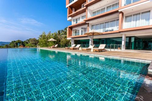 a swimming pool in front of a building at Q Kata Residence in Kata Beach