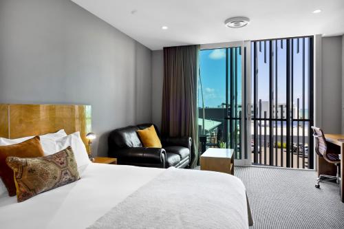 um quarto de hotel com uma cama e uma varanda em King and Queen Hotel Suites em New Plymouth