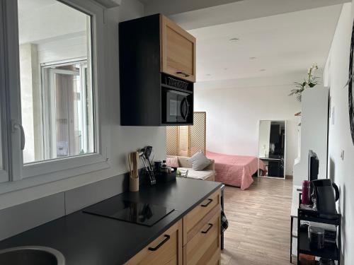 une cuisine avec un comptoir noir et un salon dans l'établissement Atelier Cosy - Parking privé gratuit, à Dijon