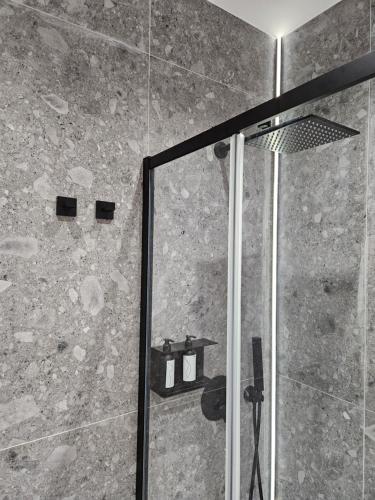 La salle de bains est pourvue d'une douche avec une porte en verre. dans l'établissement Ossidiana Rossa Elegant Suite Vulcano, à Vulcano