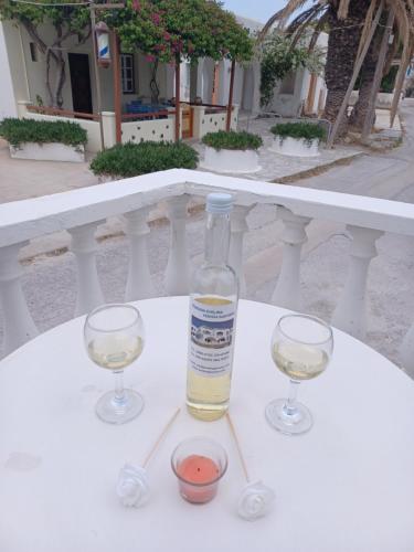 a bottle of wine and two glasses on a table at Evelina Family Beach Pension a breath away from the Black Beach offer plenty of accommodation type to suit every traveler's needs-Economic Rooms-Thematic Rooms-Design Rooms-Kitchenette Rooms-Studios-Small Apartments in Perissa