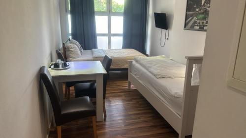 Cette chambre comprend deux lits, une table et un bureau. dans l'établissement Pension Baku, à Fürth