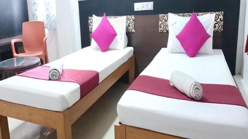two beds in a room with pink and white pillows at Bkm guest room in Chennai