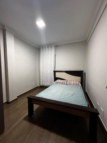 een kleine slaapkamer met een bed in de hoek bij Apartamento em área nobre in Conselheiro Lafaiete