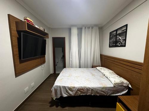 een slaapkamer met een bed en een flatscreen-tv bij Apartamento em área nobre in Conselheiro Lafaiete