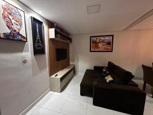 uma sala de estar com um sofá e uma televisão em Apartamento em área nobre em Conselheiro Lafaiete