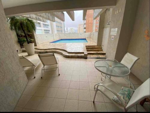 a patio with a table and chairs and a pool at Flat em Santos no Gonzaga a três quadras da praia in Santos