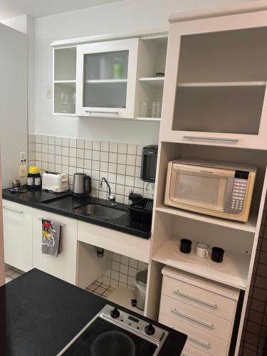 a small kitchen with a sink and a microwave at Flat em Santos no Gonzaga a três quadras da praia in Santos