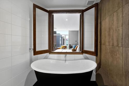 a bath tub in a bathroom with a window at King and Queen Hotel Suites in New Plymouth