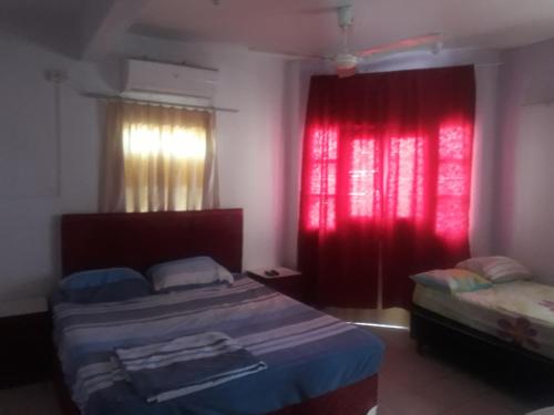 1 dormitorio con 2 camas y cortina roja en San Miguel Hostal, en Villarrica