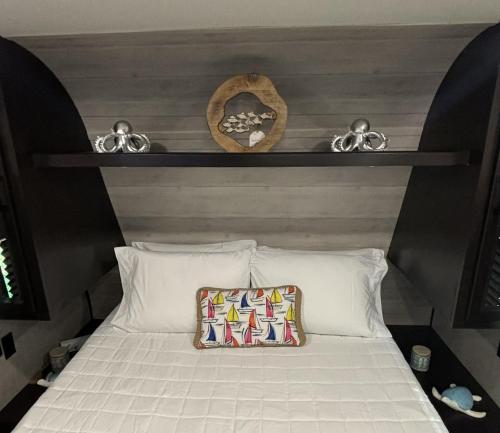 a bed with a shelf above it with a pillow at Buye Campers in Cabo Rojo