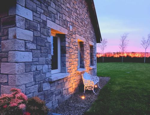 a stone building with a bench in a yard at Killossy Lodge in Naas