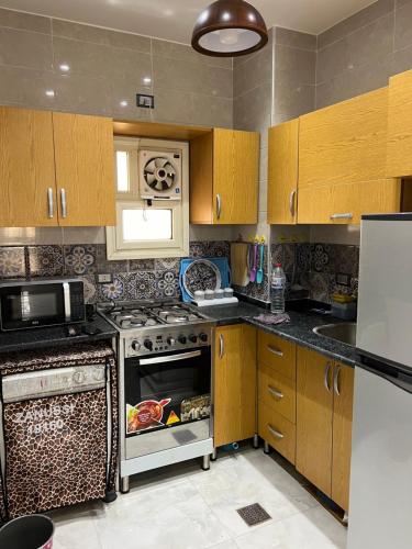 a kitchen with wooden cabinets and a stove top oven at pharma beach resort x rent قرية الصيادلة بلطيم in Al Ḩammād