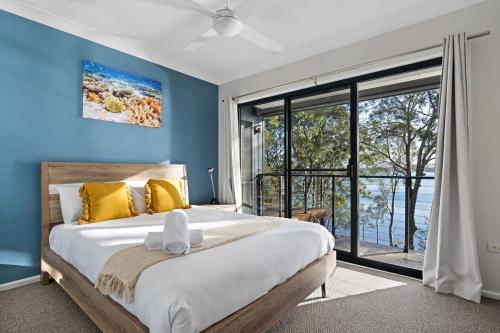 Un dormitorio con paredes azules y una cama grande con almohadas amarillas. en Tranquil Waterfront Retreat, en Wangi Wangi
