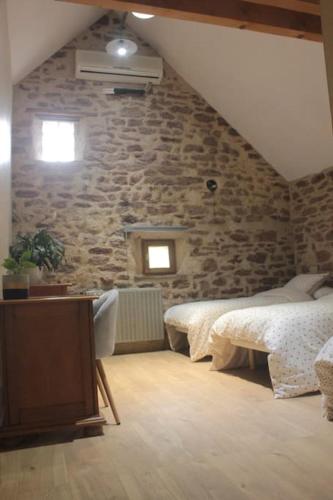 une chambre avec deux lits et un mur en pierre dans l'établissement Mine d'Ore Grand Gîte de la Chouette d'Or, à Thoste