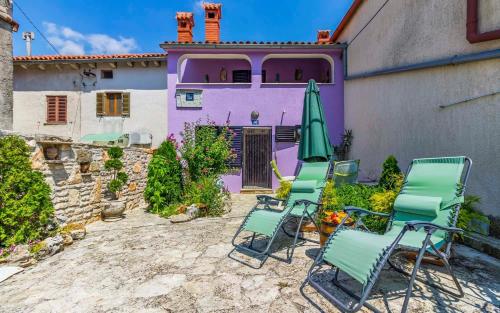 a group of chairs and an umbrella in front of a purple house at Ferienhaus für 5 Personen ca 70 qm in Rakalj, Istrien Bucht von Raša in Rakalj