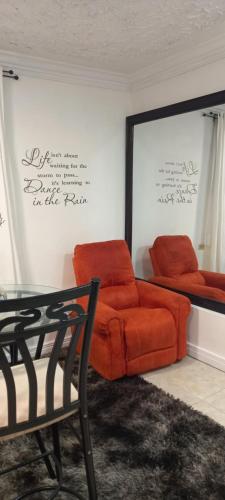 Mandeville Chateau في ماندفيل: غرفة معيشة مع أريكة برتقالية وطاولة زجاجية