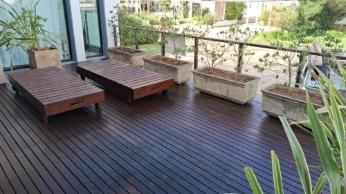 a deck with benches and potted plants on a balcony at Amplio duplex al mar en manantiales in Punta del Este