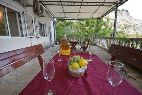 a table with wine glasses and a basket of fruit at Apartments Morinj in Donji Morinj