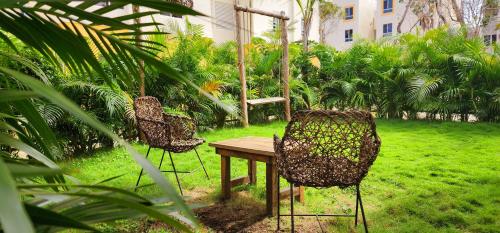 two chairs and a wooden table in a garden at Kin Tulum Apartamentos in Tulum