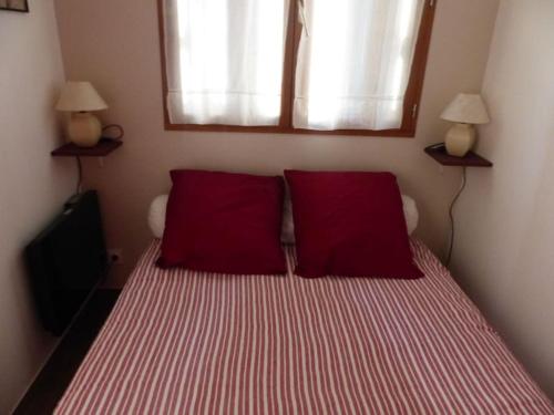 une chambre avec un lit avec des oreillers rouges et une fenêtre dans l'établissement Appart 2 chambres intramuros climatisé, à Avignon