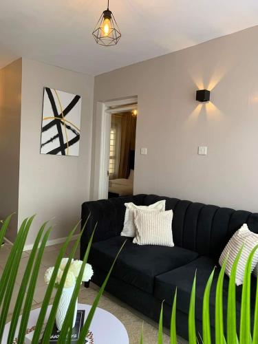 a black couch sitting in a living room at Modern One Bedroom Apartment in Kiambu