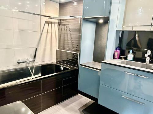 Elle comprend une petite cuisine avec des placards bleus et un évier. dans l'établissement Le coeur de Deauville, à Deauville