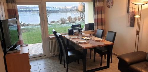 einen Esstisch mit Stühlen und ein großes Fenster in der Unterkunft Strandurlaub im Ferienappartement mit Garten - b57340 in Heiligenhafen
