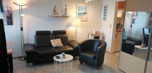 ein Wohnzimmer mit einem Sofa und einem Stuhl in der Unterkunft Strandurlaub im Ferienappartement mit Garten - b57340 in Heiligenhafen
