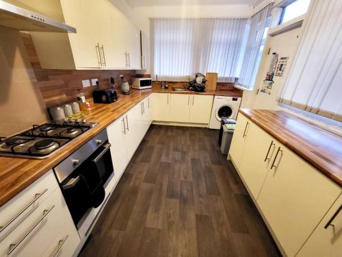 a kitchen with white cabinets and a wooden floor at Stay Sleep Rest - Grove Haven in Hull