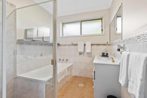 a bathroom with a shower and a tub and a sink at Swim Spa- 5mins to beach and golf - Pet Friendly in Shelly Beach