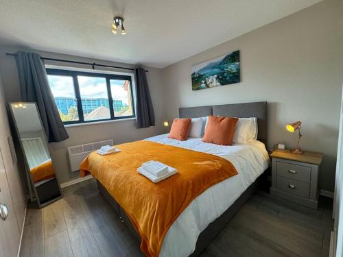 a bedroom with a large bed with an orange blanket at 2 bedroom House with Parking & Garden in Sunbury Common
